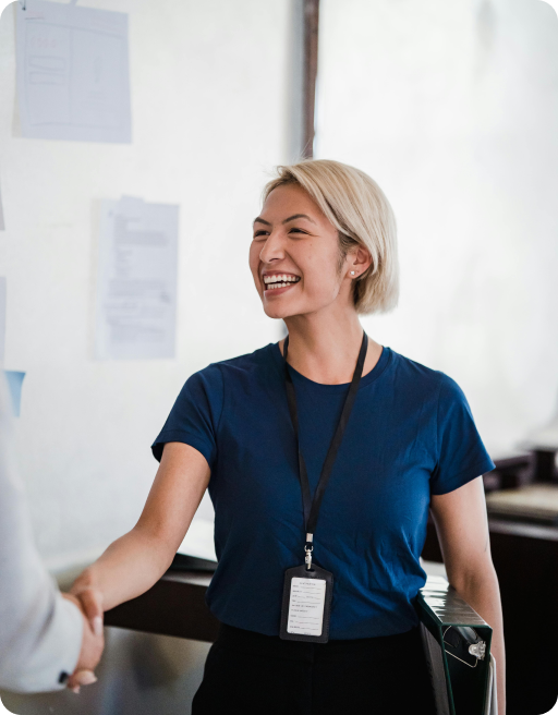 Woman in a blue shirt shaking hands with a person who is out of the frame.