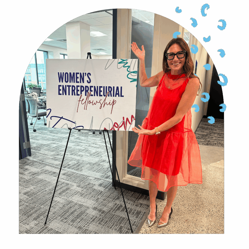 Kim Bode poses with the Women's Entrepreneurial Fellowship sign.