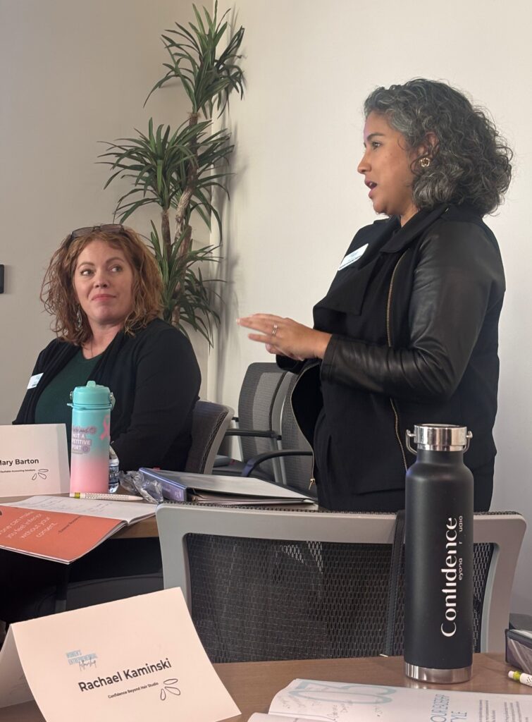 Mary Barton speaks to the cohort while Rebecca Dutcher smiles.